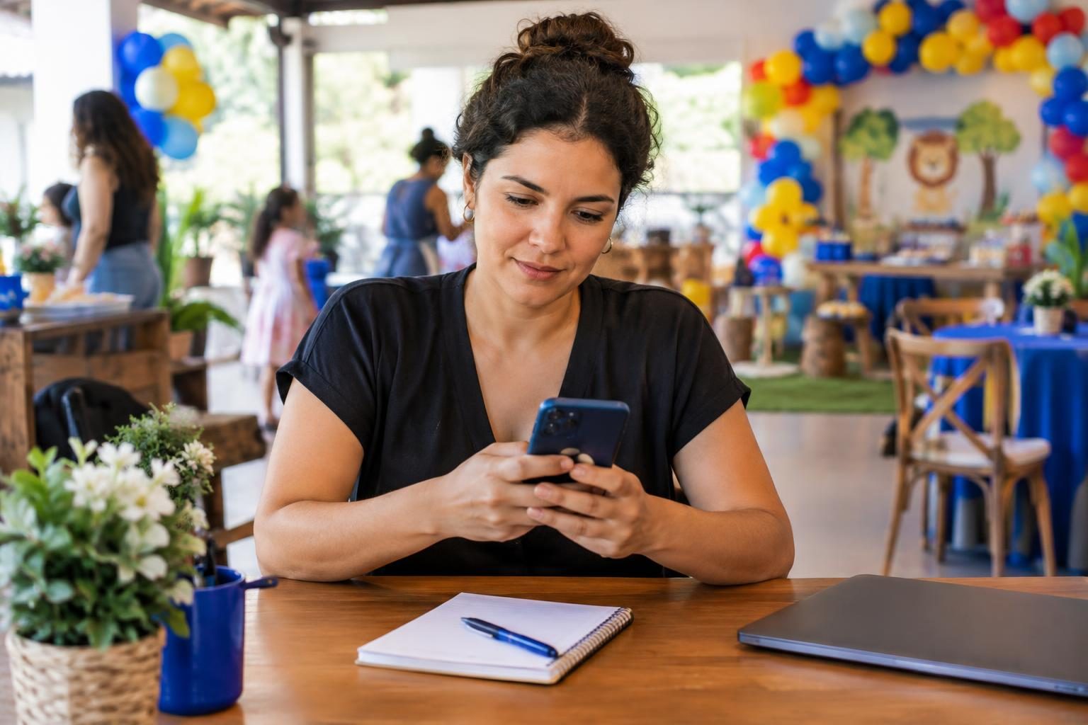 Dona de buffet infantil olhando o celular enquanto organiza o atendimento de clientes
